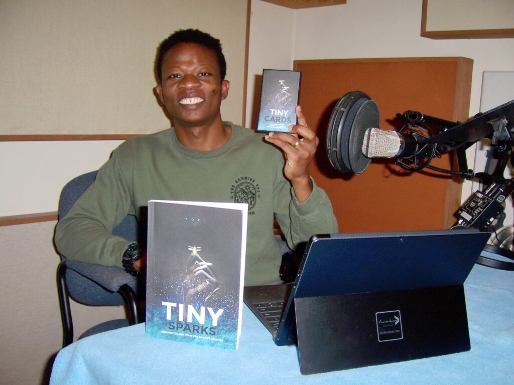 Kofi Douhadji displays "Tiny Sparks" book and cards at Tesco Productions.